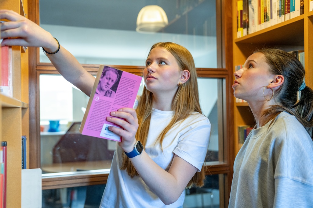 Leerling zet boek terug in kast