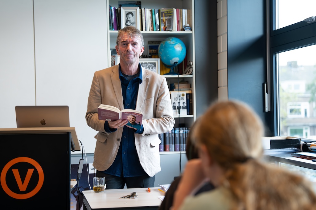 Mannelijke docent en leraar Nederlands staat voor de klas met een boek